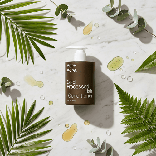 Act+Acre Cold Processed Hair Conditioner with botanical leaves on white marble