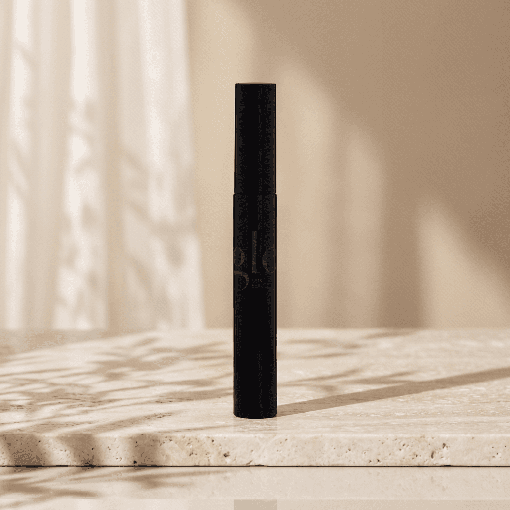 Glo black mascara tube on ivory travertine with a champagne background