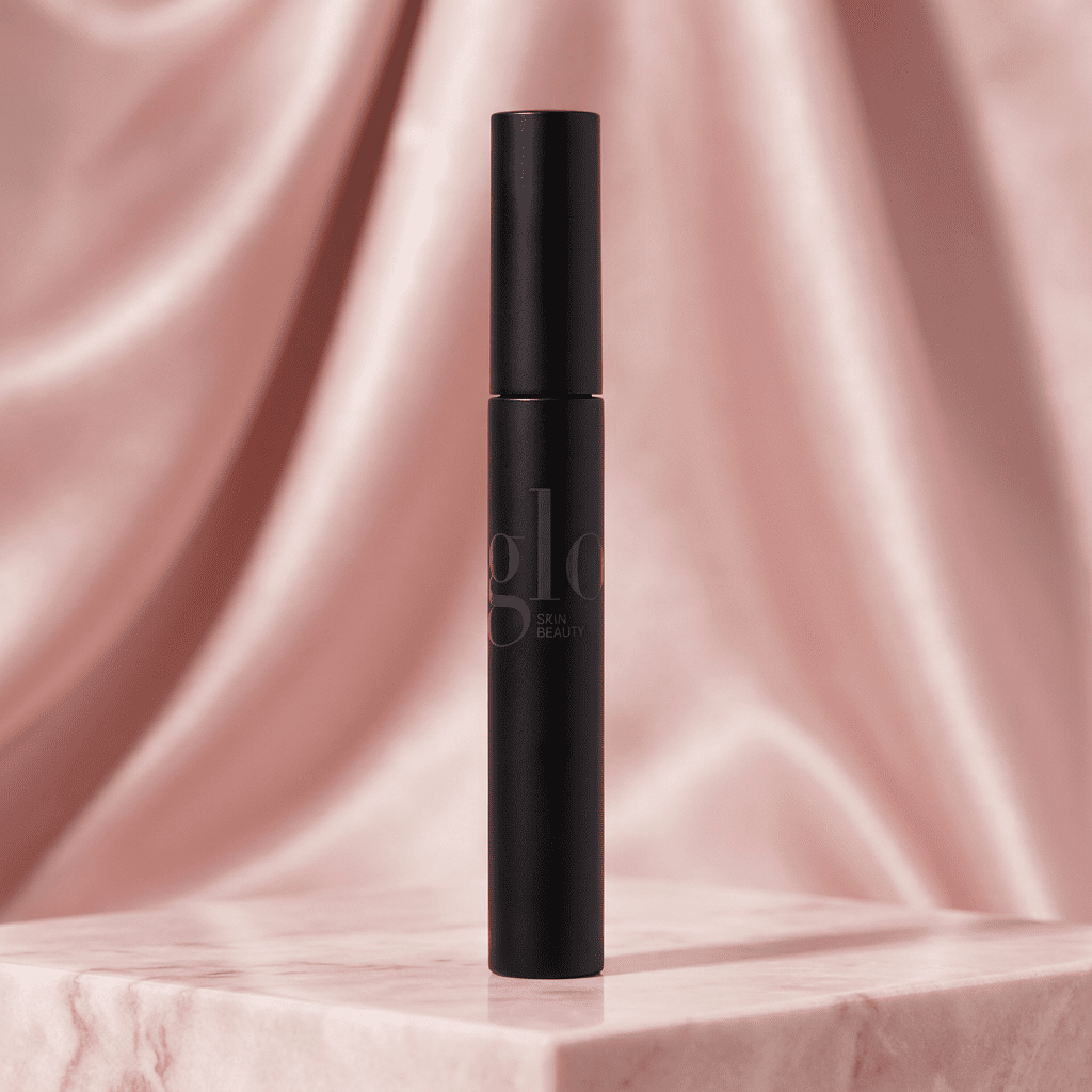 Glo black mascara tube on a blush pink pedestal with a rose satin background